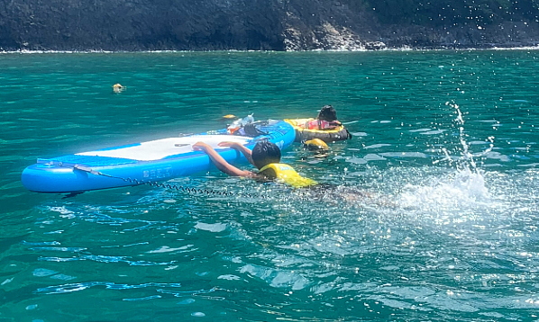 SUPボードに掴まりながら海を泳ぐバタ足トレーニング