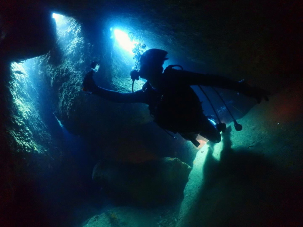 雲見・三角穴下のステージでGoProを片手に水中撮影を楽しむダイバーのシルエット