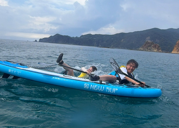 バランスを崩して海へ落ちて大笑いするカップル