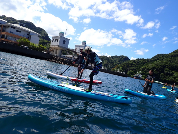 安良里の弁天島を目指して強風に立ち向かうSUPツアーの様子