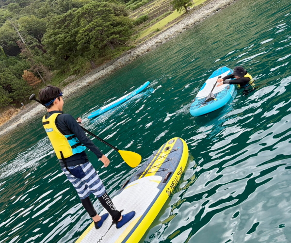 海にドボンしたパパとママをSUPボードの上から笑顔で応援する子供