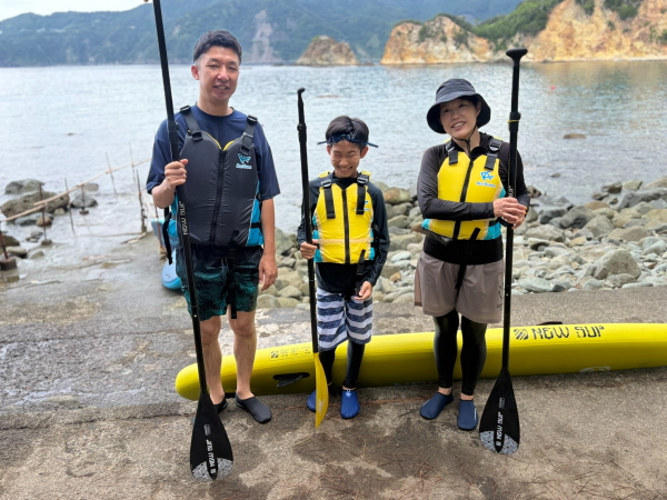 黄金崎の海でSUPを楽しむご家族の様子