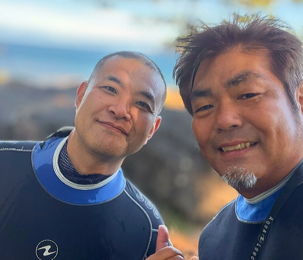 黄金崎の美しい海を背景に笑顔を見せる男一人旅のゲスト様